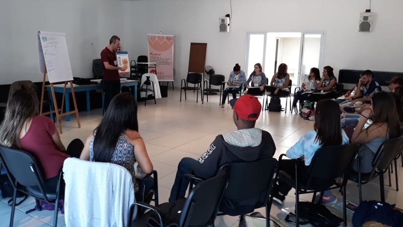 Adolescentes estão sentados em roda, em uma sala de aula. Eles participam do programa Jovens Mobilizadores.