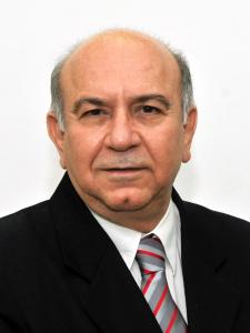 Foto do médico Halim Girade. Ele é branco, calvo, cabelos grisalhos e veste um terno.